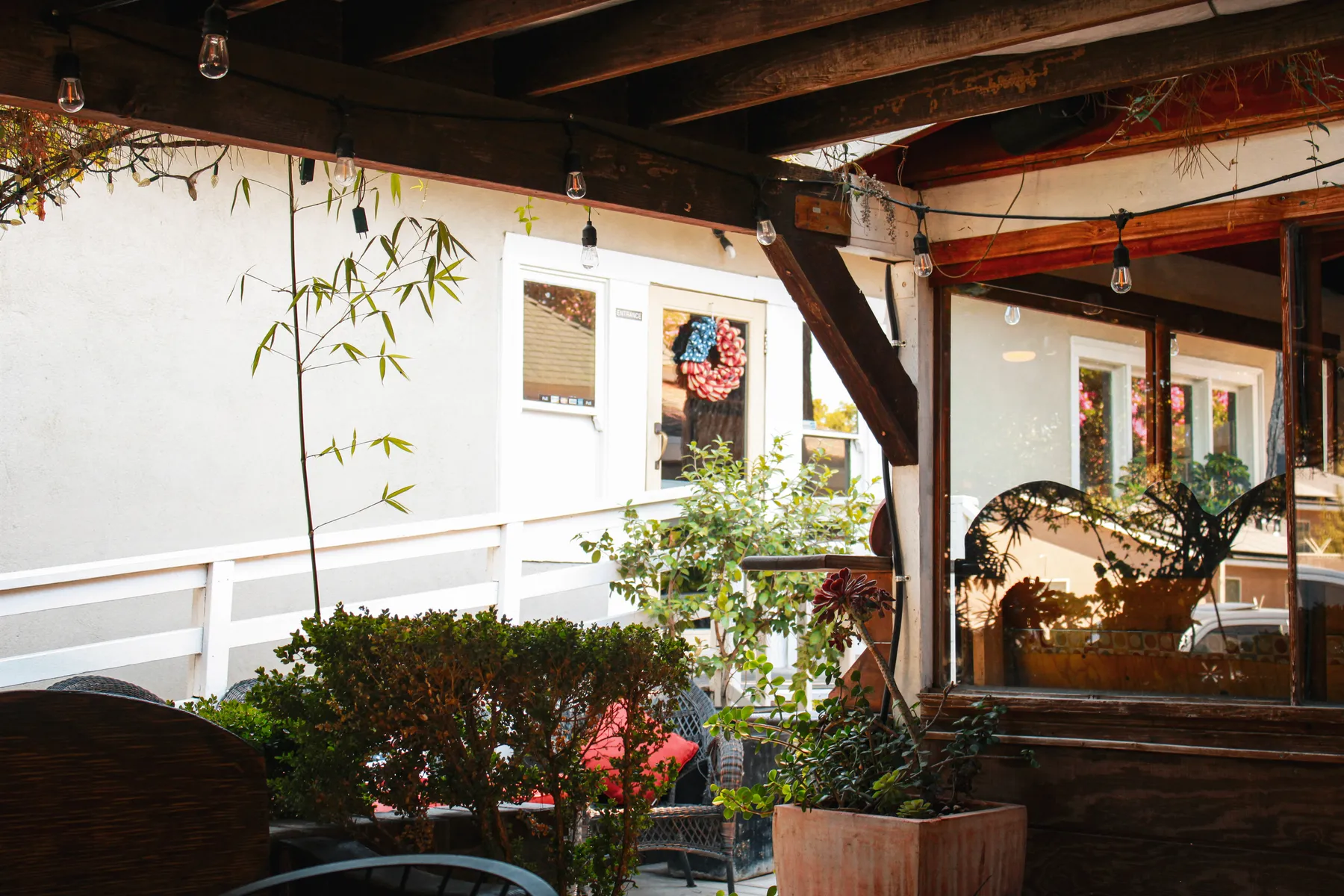 Wicker patio seating beneath string lights and bamboo at El Jardín